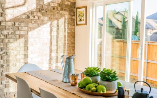 black kettle beside condiment shakers and green fruits and plants on tray on brown wooden table