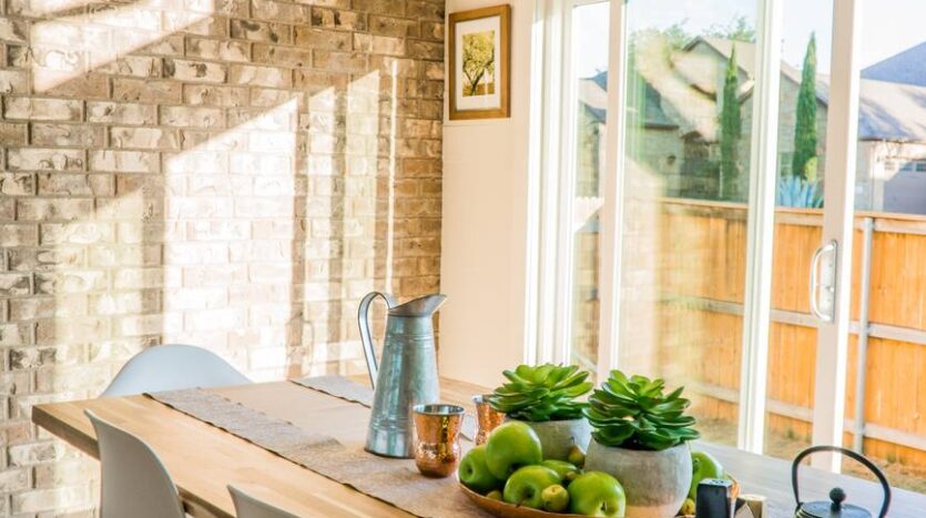 black kettle beside condiment shakers and green fruits and plants on tray on brown wooden table