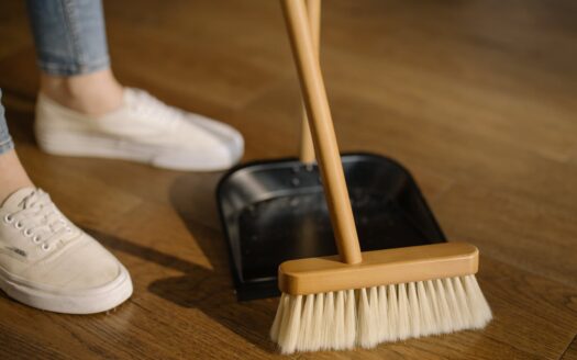 person wearing white pants and white socks standing beside brown broom