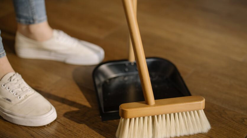 person wearing white pants and white socks standing beside brown broom