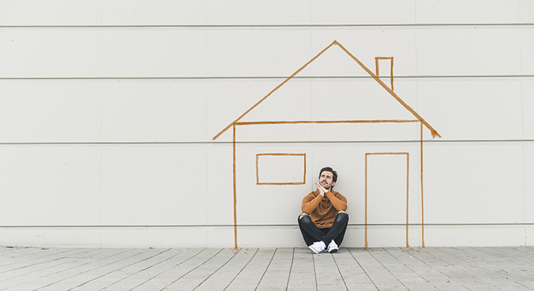 Digital composite of young man sitting at a wall with a house