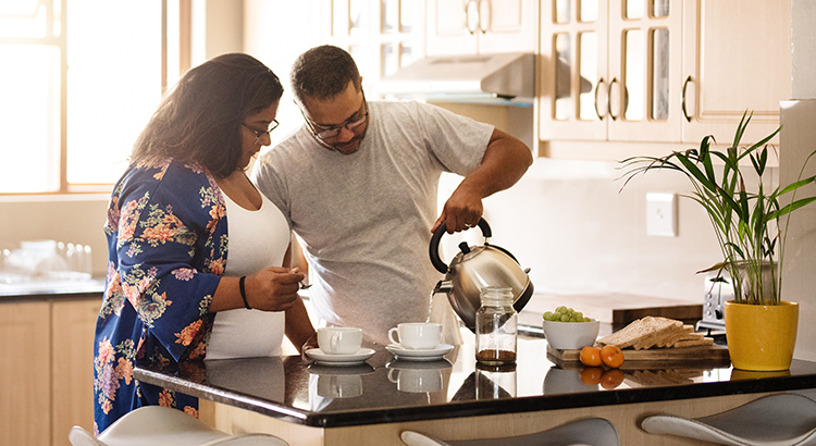 Shot of a man pouring coffee in cups on kitchen counter with his wife standing by