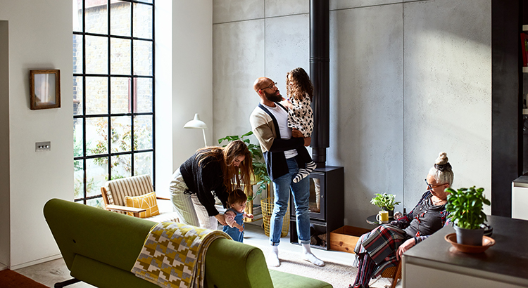 Parents with two children in living room, with grandmother, father holding young girl, mother playing with toddler
