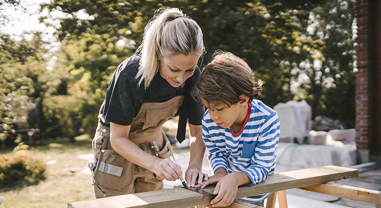 Mother measuring wooden plank by son at construction site