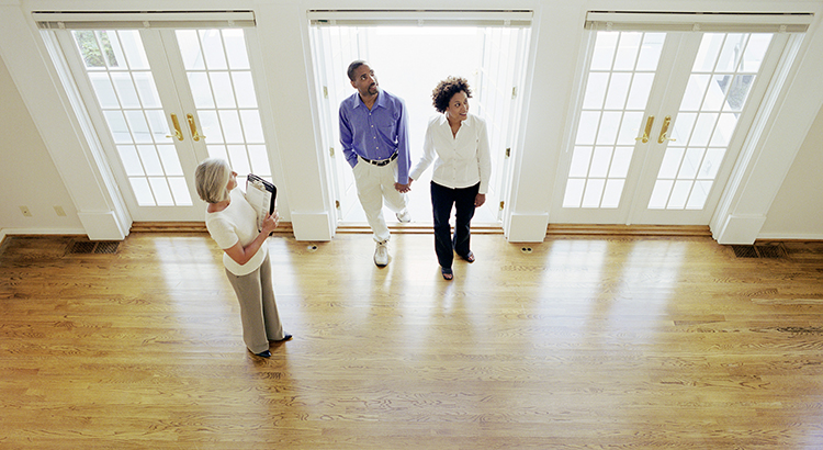 Mature realtor showing couple interior of house, elevated view