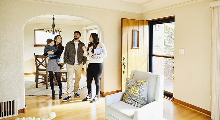 Wide shot for family with toddler in discussion with real estate agent while looking home for sale during open house