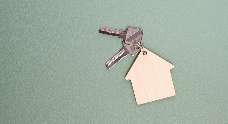 Keychain in form house with keys green background.Concept buying house, apartment or rent