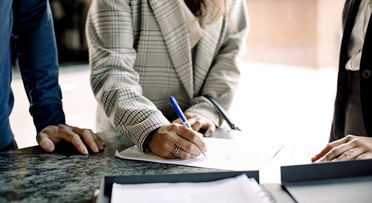 Midsection of couple signing contract with real estate agent in kitchen