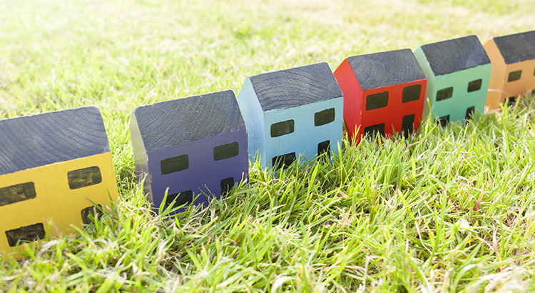 Row of wooden toy houses on grass