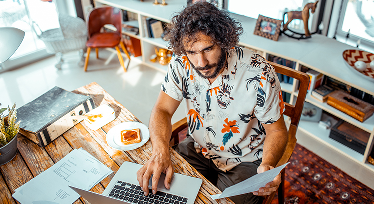 Close up of a young man working on his laptop from home