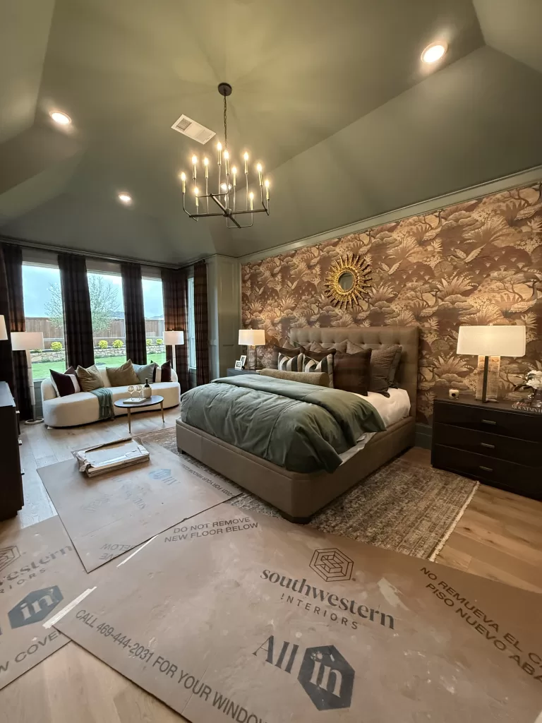 Highland Homes Furst Ranch primary bedroom with green bedding, wallpaper accent wall, chandelier, and designer furnishings.