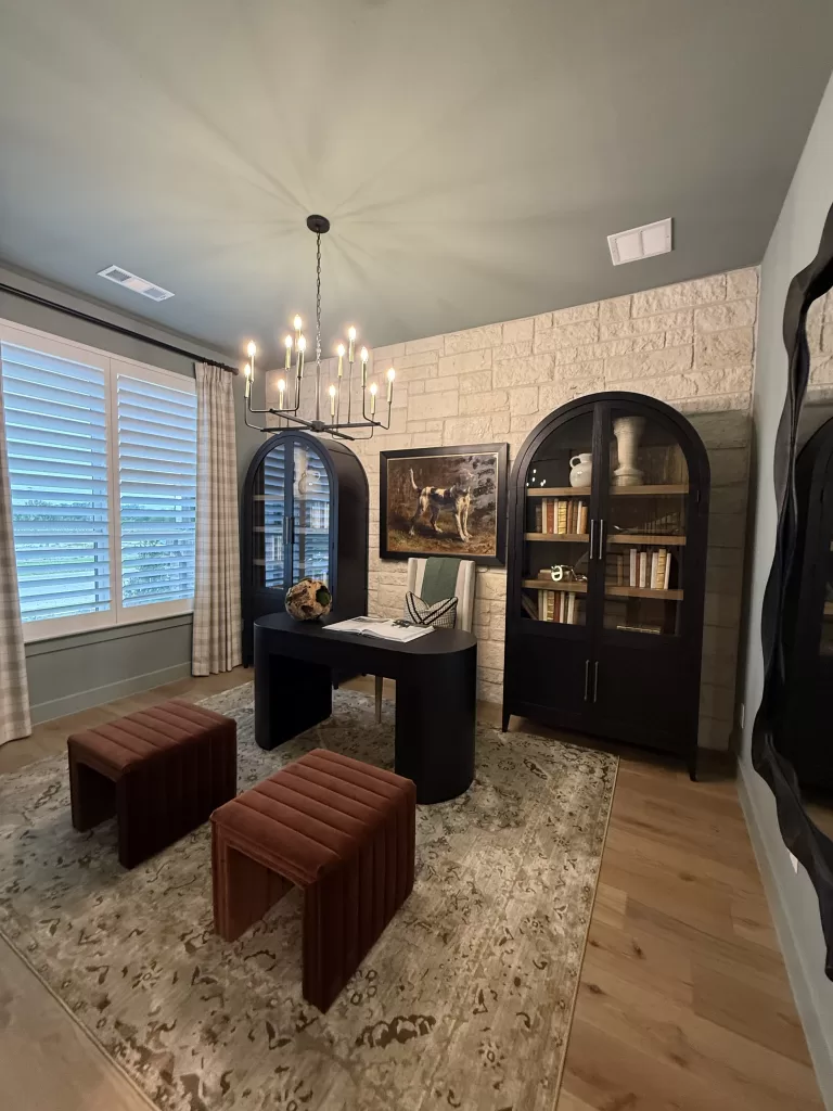 Highland Homes Furst Ranch study with black desk, arched cabinets, stone wall, rug, and chandelier.