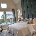 Primary suite in a David Weekley Homes model at Furst Ranch, featuring vaulted ceilings, large windows, upholstered accent wall, and designer finishes near Flower Mound and Bartonville, TX.