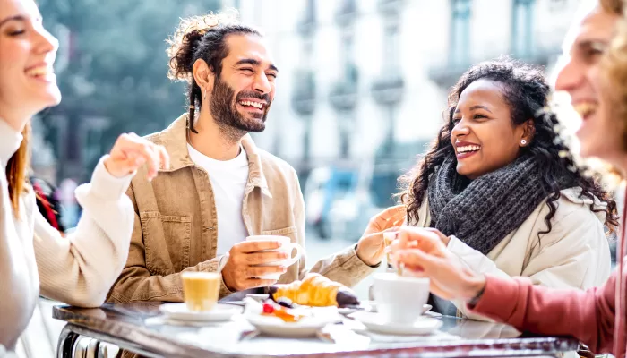 Young couples drinking cappuccino at coffee bar patio - Friends talking and having fun together at sidewalk cafeteria - Life style concept with young men and women at cafe dehor - Bright vivid filter